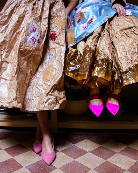 Photo, from the waste down, of two women wearing brown paper skits and vivid pink shoes