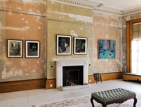 View of drawing room, including white marble fireplace, and showing artworks on the wall.