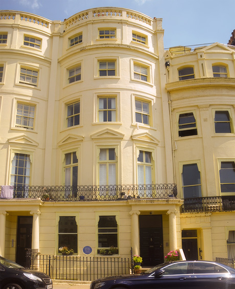 Colour photo of a five-storey Regency building with a cream stuccoed facade. The upper four storeys are bow-fronted above a straight, rusticated ground floor.