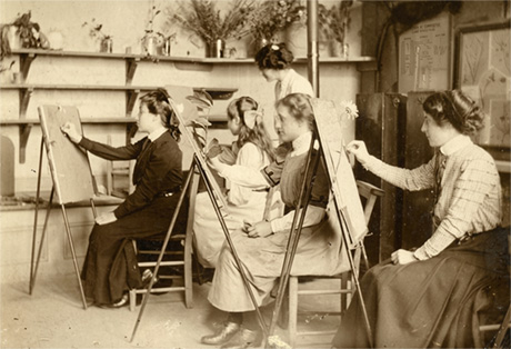 Early photograph of an art studio where a group of women are sat at their easels and drawing