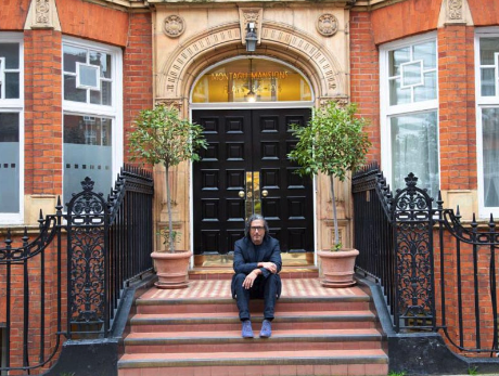 Photograph of a man sat on the steps of a historic building.