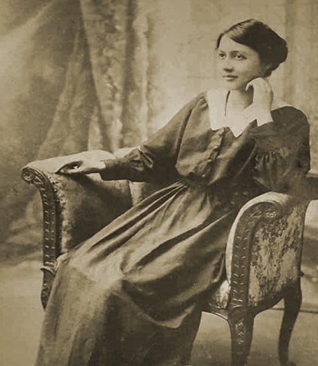 A sepia-toned photo of a young woman, seated and wearing a plain dark dress.